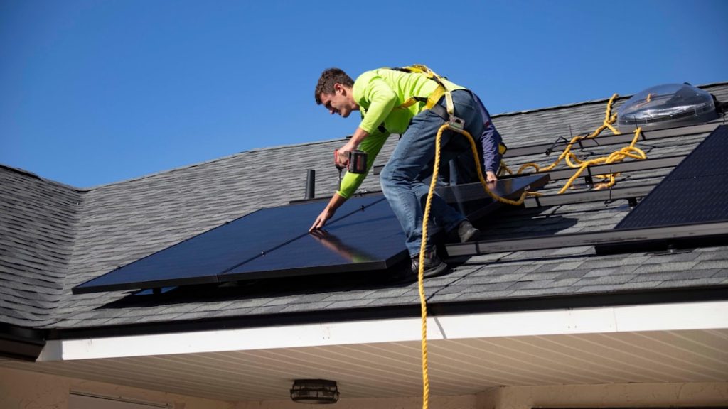 a man on a roof installing a solar panel